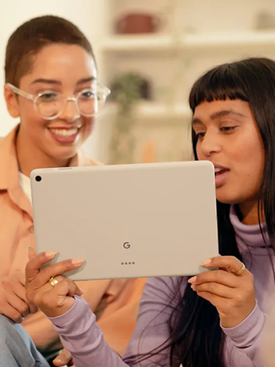 Two people smile while looking at a tablet.